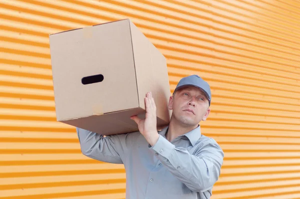 Elinde karton bir kutuyla gri takım elbiseli bir adam. Posta teslimatı konsepti