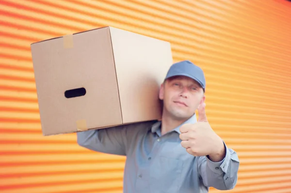 Elinde karton bir kutuyla gri takım elbiseli bir adam. Posta teslimatı konsepti