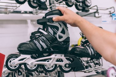 Adam spor mağazasında patenleri elinde tutuyor.