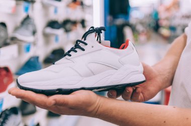 Süpermarkette elinde spor ayakkabıları tutan bir adam.