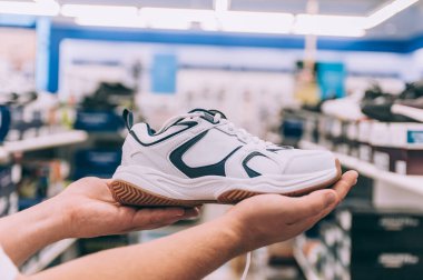 Süpermarkette elinde spor ayakkabıları tutan bir adam.