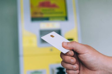 Adamın biri ATM 'nin arka planında kredi kartı tutuyor.