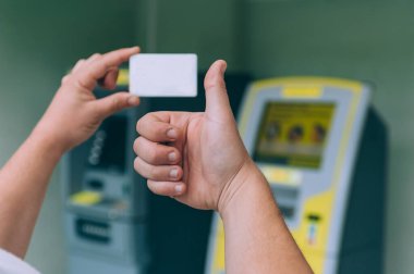Adamın biri ATM 'nin arka planında kredi kartı tutuyor.