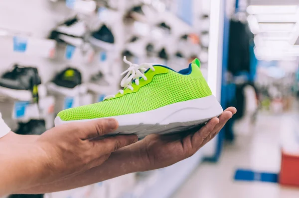 Süpermarkette elinde spor ayakkabıları tutan bir adam.