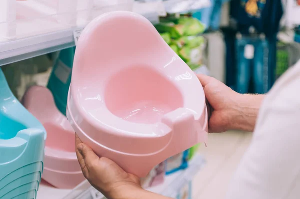 Bir adam dükkanda bebek için lazımlık seçer.