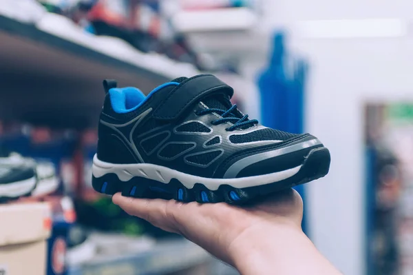 Süpermarkette adamın biri elinde spor ayakkabı tutuyor.