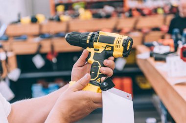 Elinde matkap tutan bir adam var. Konsept adam bir hırdavatçıdan ürün seçer.