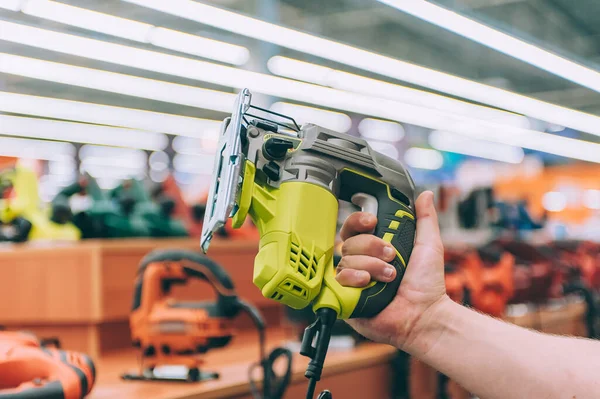 Kesmek için yapboz tutan bir adam. Konsept adam bir hırdavatçıdan ürün seçer.