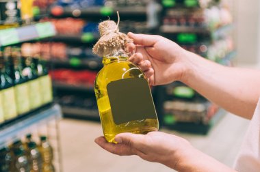 Bir adam elinde bir şişe zeytinyağı tutuyor. Kavram adamı bir mağazadan ürün seçer.
