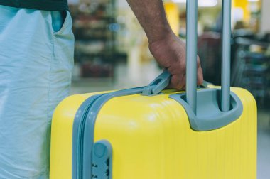 Sarı bavullu bir adam havaalanına geziye gidiyor.