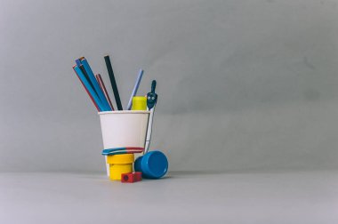 Okula Dönüş Konsepti. Gri arka planda beyaz camlı boyalar ve kalemler.