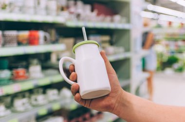 Süpermarkette bir adam elinde pipetle içki tutar.
