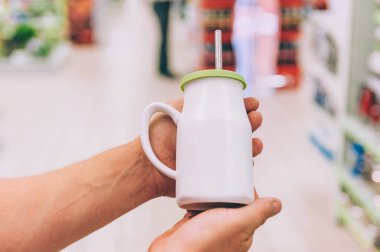 Süpermarkette bir adam elinde pipetle içki tutar.