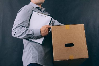 Elinde karton kutu olan bir adam. Koyu arkaplanda teslimat hizmeti kavramı