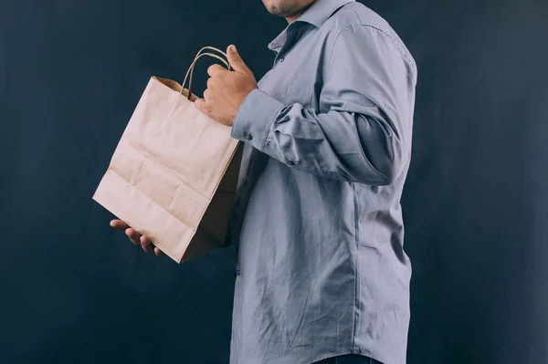 Man with a cardboard bag in his hands. Delivery service concept on dark background