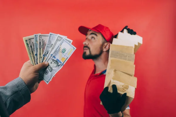 The boss pays money to his employee with dollars in hand. Concept on a red background