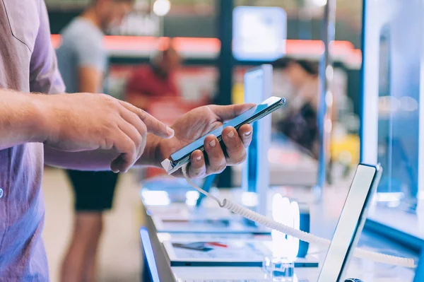 Süpermarketteki adam akıllı telefon seçiyor.