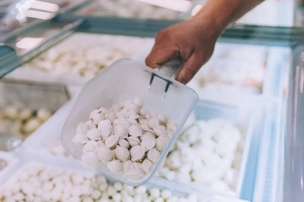 Süpermarketteki adam buzdolabından hamur tatlısı seçiyor.