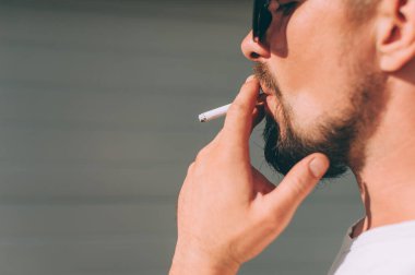 Elinde sigara olan bir adam sigara içiyor.