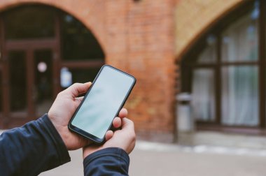 Model teknolojisi. Adam akıllı telefonu yakın planda tutuyor.
