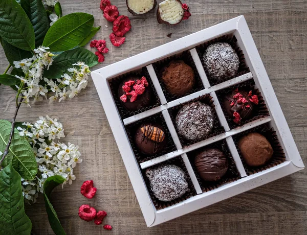 gift set of truffles made from real Belgian handmade chocolate with various additives in the form of nuts and berries on a dark background with a beautiful design on a box