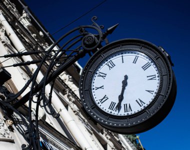 Gökyüzüne karşı eski tarzda yuvarlak metal bir saat.