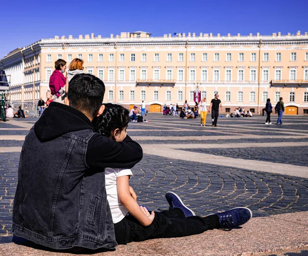 Saint Petersburg / Rusya 23.06.2020: Baba ve kızı şehrin merkez meydanında oturuyorlar ve binalara yan gözle bakıyorlar