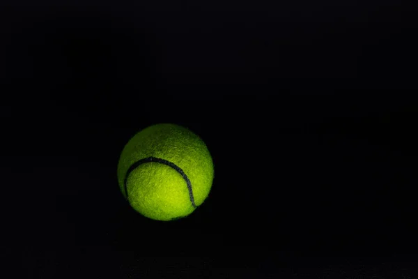 stock image tennis ball isolated on dark background in hard light