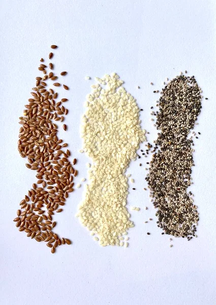 Chia seeds, flax seeds, sesame seeds on white background, scattered seeds, healthy food, super foods, vertical lines