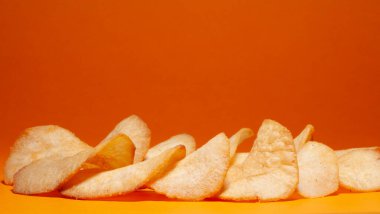 Turuncu arkaplanda izole edilmiş lezzetli patates cipsi.