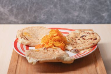 El Salvador 'dan gelen geleneksel peynirli pupaların cezbedici yayılımı, kırmızı ve beyaz kırsal bir tabağın tepesinde curtido ile servis edilir..