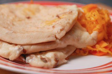 Kırsal tabaktaki peynir pupaları, canlı kürtido ile tamamlanmış, El Salvador 'un mutfak mirasının simgesi.