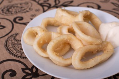 Tabakta mayonez ile kızarmış mürekkep balığı halkaları.