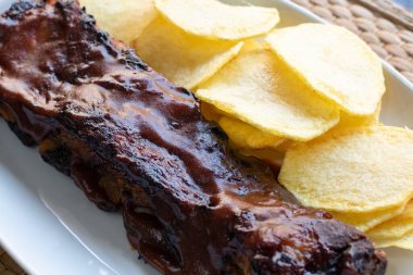 Yanında dilimlenmiş patatesli ev yapımı barbekü pirzolası.