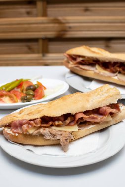 Pişmiş pastırma ve peynirli baget sandviç ve salata.