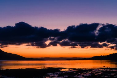 İskoçya 'nın batı kıyısındaki Arran Adası' ndaki Lamlash adasından alınan güneş kışın doğarken Lamlash Körfezi 'nden anakaraya doğru bakıyor..