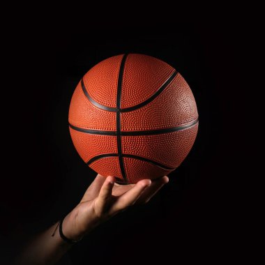 Basketball on hand, black background                           