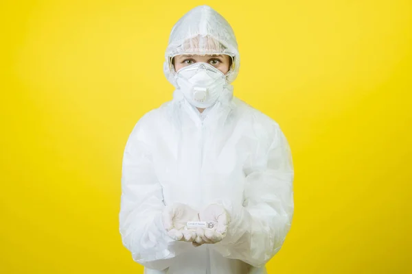 inventor girl in a protective suit, mask and gloves carefully holds in her hands the coronovirus vaccine against COVID-19