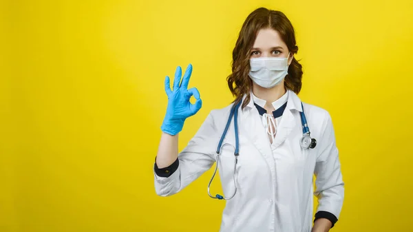 doctor womdoctor woman in mask and gloves shows okay sign on a yellow background. Banner. Free spacean in mask and gloves shows okay sign on a yellow background. Banner. Free space