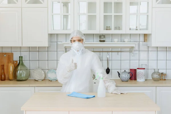 A professional pest or virus contractor stands in the kitchen and shows a positive sign. The concept of a pandemic coronavirus disinfection or COVID-19