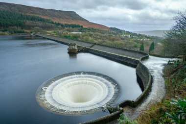 Ladybower Reservoir is the lowest of three reservoirs in the Upper Derwent . The dam's design is unusual in having two totally enclosed bellmouth overflows (locally named the 