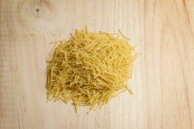 Hafif ahşap masada çiğ erişte yığını.