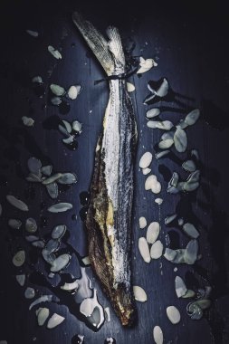 Durgun bir hayat, kırmızı deniz mavisi bir masada kurutulmuş, badem ve zeytinyağıyla uçan bir balığın ışık boyama tekniğiyle alınır. Malaga ve Cadiz bölgesinden tipik bir yemek (Endülüs, İspanya)