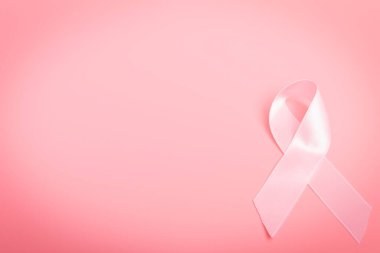 Pembe arka planda pembe fiyonk. Kravat, farkındalığın evrensel bir sembolü ve göğüs kanserine karşı verilen mücadeledir..