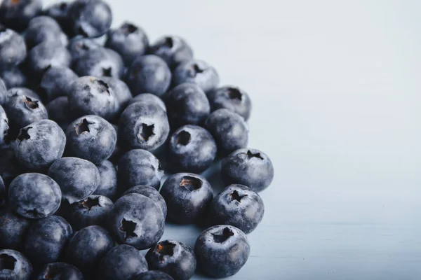 Group of blueberries located to the right on a light blue wooden background.