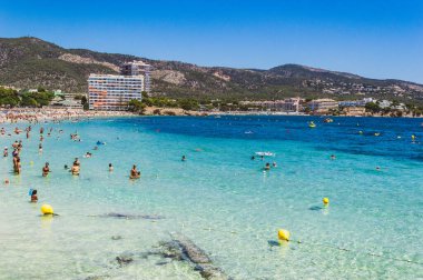 MAGALUF, MALLORCA, İSPA, 17 Temmuz 2016: İnsanlar İspanya 'nın Magaluf kentindeki kristal berrak deniz suyunun tadını çıkarıyor. Magaluf, İspanya, Mavi Bayrak ile ödüllendirilen sahilde kristal berrak bir su.