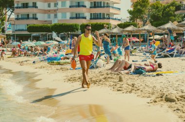 MAGALUF, İspanya, 22 Temmuz 2016: İspanya 'nın Palma de Mallorca kentinde yaz günü boyunca bir cankurtaran plajda yürüyor.