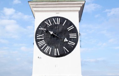 Siyah arka planda beyaz Roma rakamları olan eski bir kule saati. Sırbistan 'ın Novi Sad kentindeki Petrovaradin kalesinde eski bir kule saati bulundu.