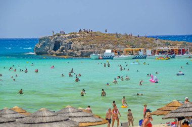 NISSI BEACH, AYIA NAPA, CYPRUS, 17 Temmuz 2017: Turistler Kıbrıs Rum Kesimi 'nin Ayia Napa kentinde popüler Nissi Sahili' nin turkuaz ve sığ sularında banyo yapıyorlar.