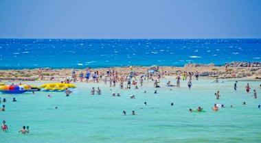 NISSI BEACH, AYIA NAPA, CYPRUS, 17 Temmuz 2017: Turistler Kıbrıs Rum Kesimi 'nin Ayia Napa kentinde popüler Nissi Sahili' nin turkuaz ve sığ sularında banyo yapıyorlar.